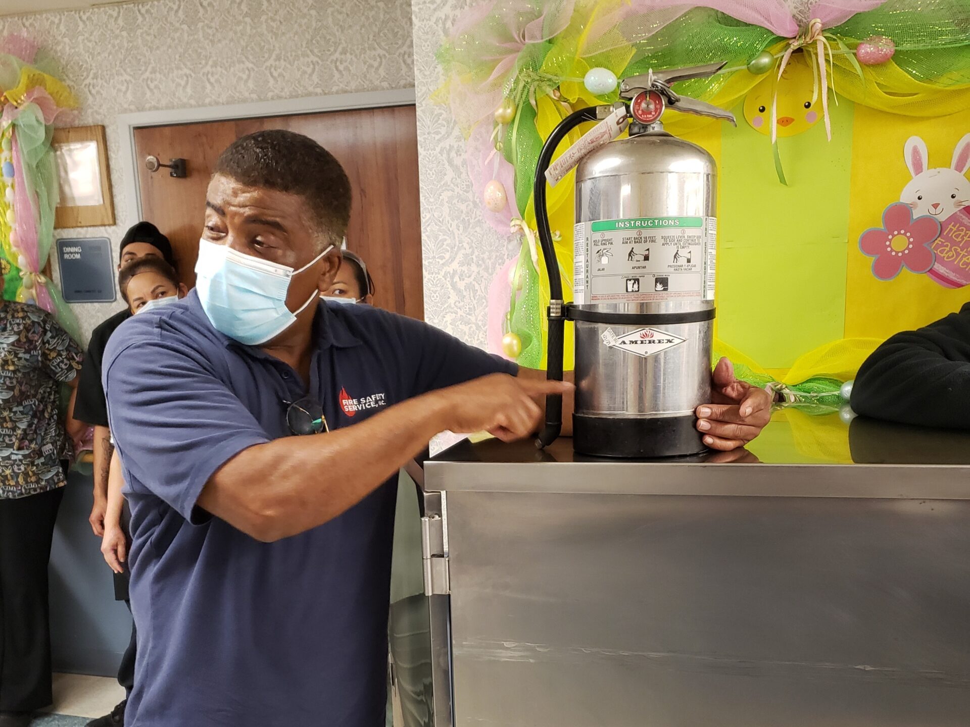 Instructor demonstrating a fire extinguisher to facility staff